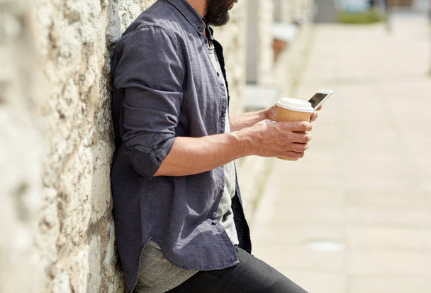 man with smartphone drinking coffee on city street - Foto, Imagen