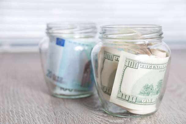 Geld. Dollars en euro in twee open potten op grijze houten achtergrond. Kopiëren van ruimte. - Foto, afbeelding