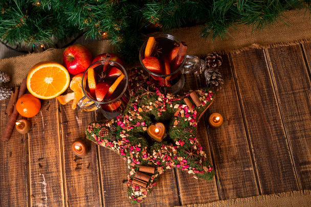 Kerstster in de buurt van glühwein met vruchten en kruiden op houten tafel. Xmas decoratie op achtergrond. Twee glazen. Winter opwarming van de aarde drinken recept ingrediënten rond. bovenaanzicht. - Foto, afbeelding