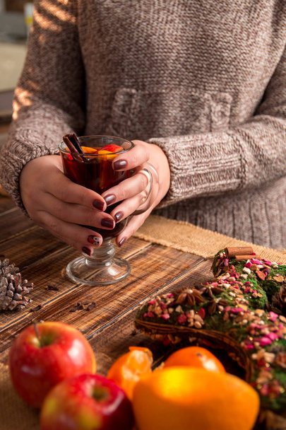 Christmas. Mulled wine in female hands, spices and fruit ingredients  on wooden table. Winter warming drink.  - Foto, Imagem