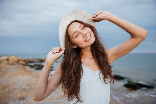 lächelnde süße junge Frau mit Hut am Strand - Foto, Bild