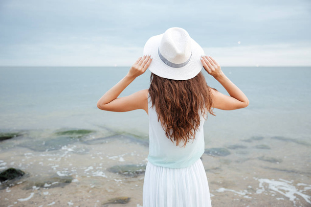 Back view of woman standing and looking at the sea - Foto, imagen