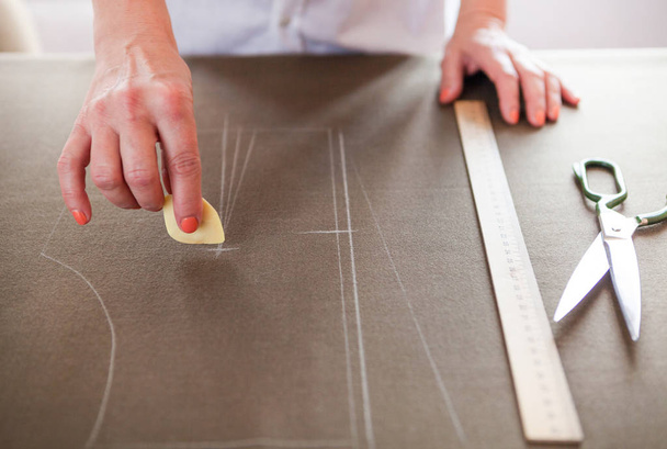 Close up. Hands woman Tailor working cutting a roll of fabric on - 写真・画像