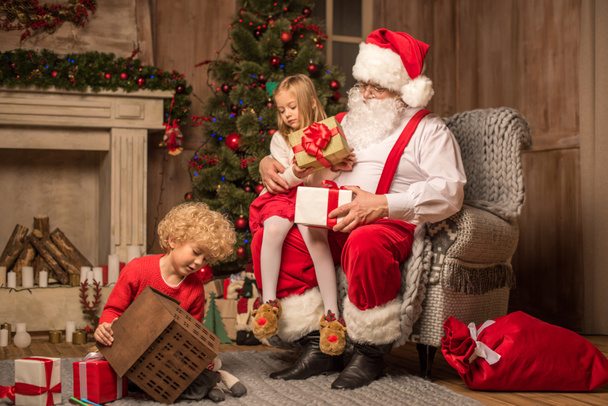 Santa Claus with children sitting near fireplace  - Fotoğraf, Görsel