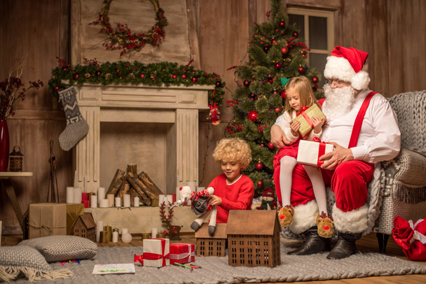 Santa Claus and children sitting near fireplace - Photo, Image