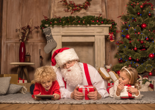 Kerstman en kinderen liggen op tapijt - Foto, afbeelding