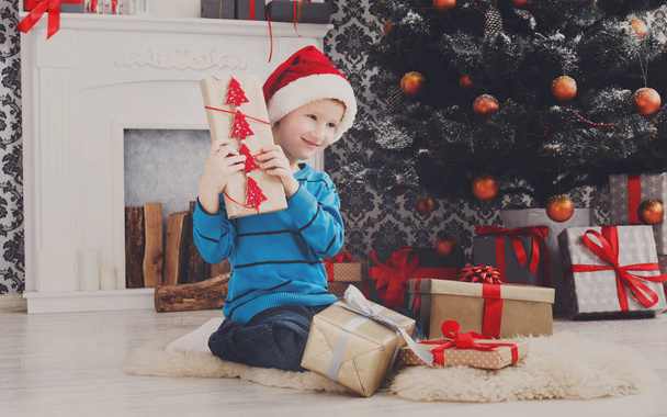 Roztomilý chlapec v santa hat rozbalení vánoční dárky - Fotografie, Obrázek