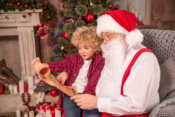 Santa Claus and child reading wishlist - Foto, immagini