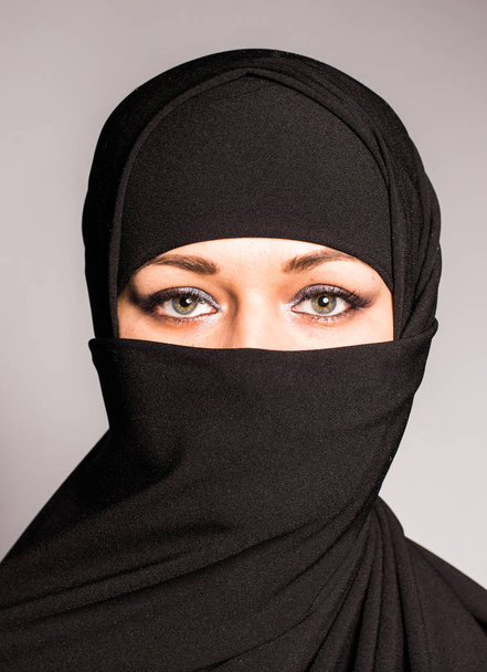 Portrait of an arabic young woman with her beautiful blue eyes in traditional islamic cloth niqab. - Photo, Image
