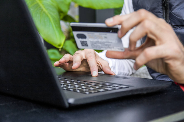 Man holding a credit card and typing. On-line shopping on the internet using a laptop. Close Up Of A Man Shopping Online Using Laptop With Credit Card - Фото, изображение