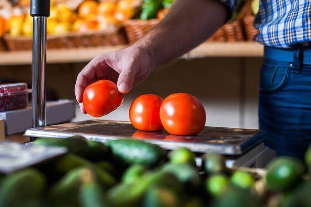 Продавец кладет помидоры на весы
 - Фото, изображение