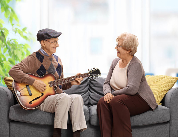 Elderly man playing a guitar to an elderly - Fotoğraf, Görsel