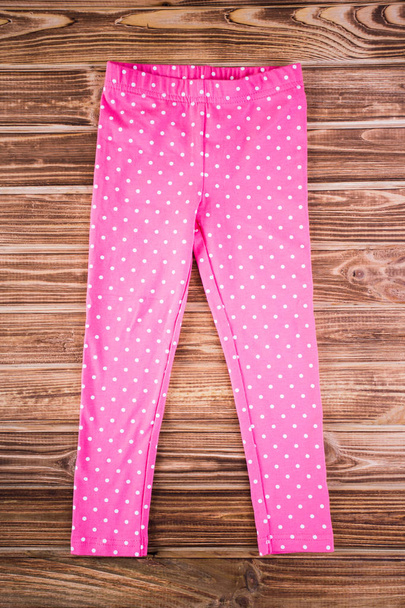 Elegante bebé pantalones de color rosa en el fondo de madera
 - Foto, imagen