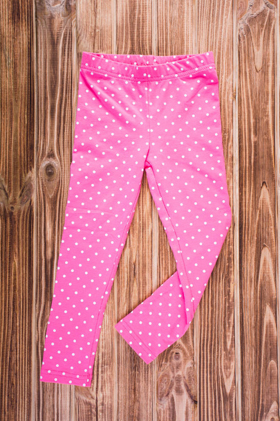 Eleganti pantaloni rosa bambino sullo sfondo in legno
 - Foto, immagini
