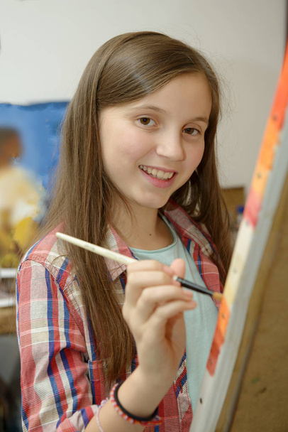 Sorrindo jovem adolescente pintando uma tela
 - Foto, Imagem