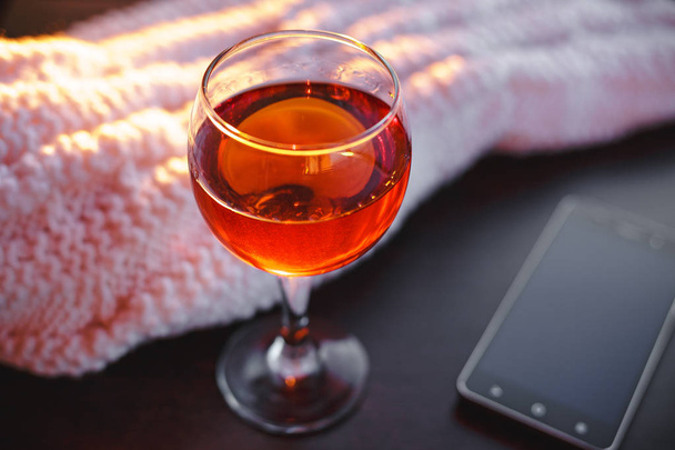 Vin rouge et téléphone portable avec couverture blanche.Soirée douce.Image bokeh tonique
. - Photo, image