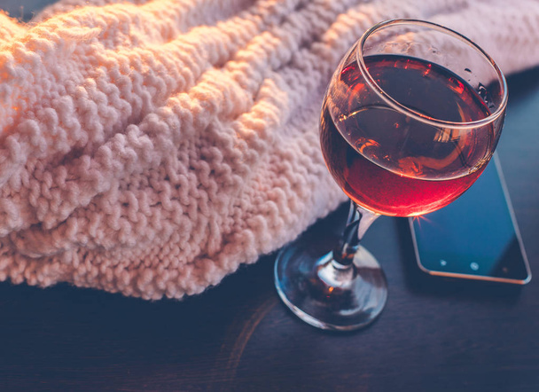 Red wine and mobile phone with white blanket.Sunny evening.Toned bokeh image. - Photo, Image
