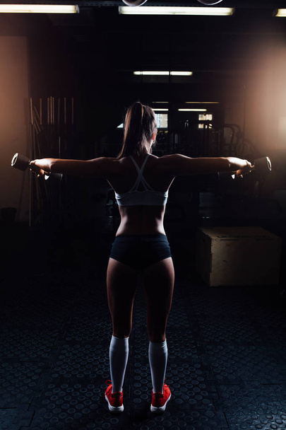 Beautiful fitness woman with lifting dumbbells . - 写真・画像