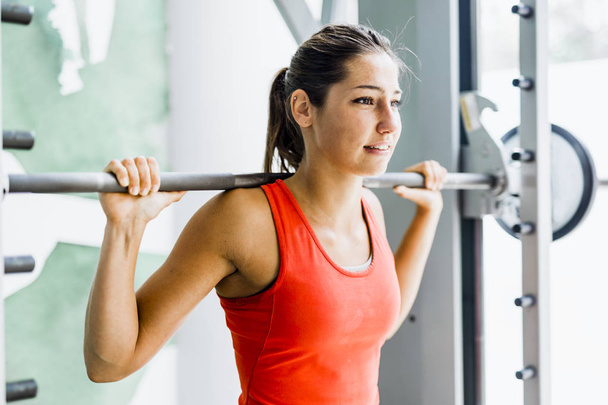 Молодая красивая женщина поднимает тяжести в спортзале
 - Фото, изображение
