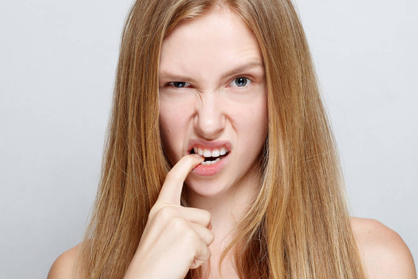 Portrait of nervous pretty young woman biting her nails - 写真・画像