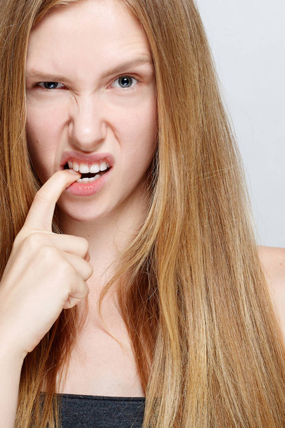 Portrait of nervous pretty young woman biting her nails - Fotografie, Obrázek