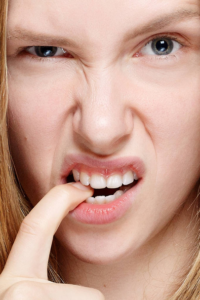 Retrato de una mujer joven y nerviosa mordiéndose las uñas
 - Foto, imagen