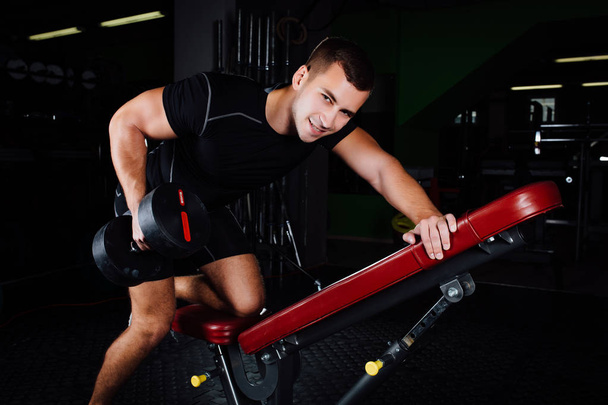 Atletický muž vzpírání v tělocvičně na lavičky s činka. - Fotografie, Obrázek