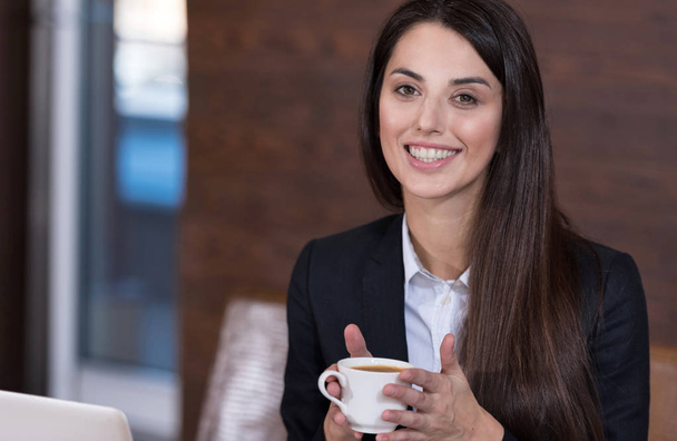 Beautiful woman drinking coffee in a office - Photo, image