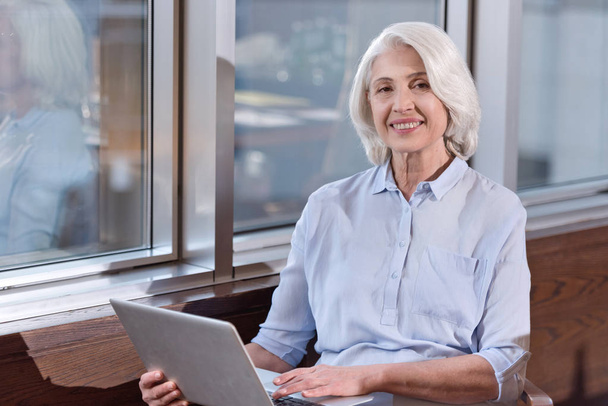 Elderly woman working on laptop in an office - Foto, Imagen
