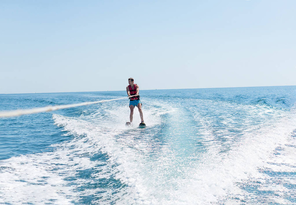 Young man glides on water skiing on the waves on the sea, ocean. Healthy lifestyle. Positive human emotions, feelings, joy. - Photo, Image