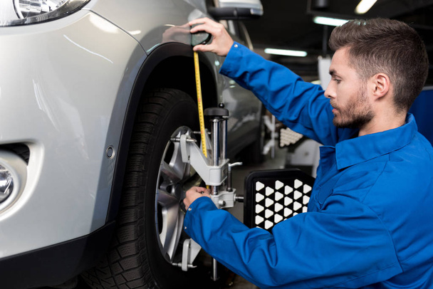 Professional mechanic adjusting automobile wheel alignment - 写真・画像