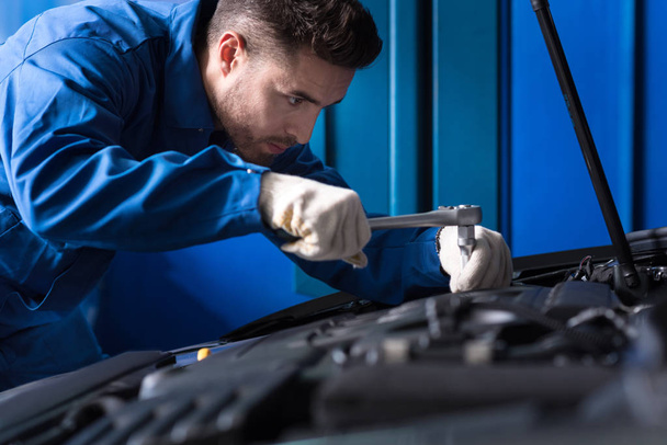 Concentrated mechanic repairing car engine - Foto, Bild