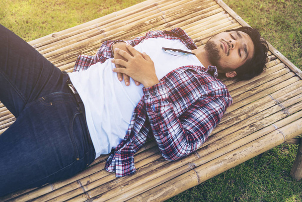 Young man take nap on bamboo bed or seat - Фото, зображення