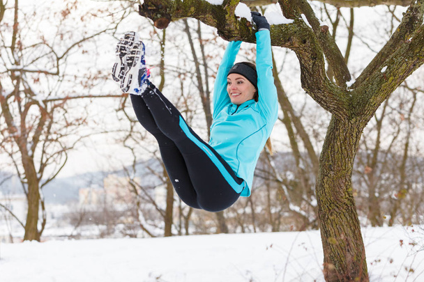 Winter sports, girl exercising on tree. - Fotó, kép