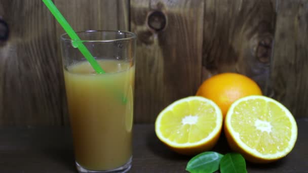 Pomerančová šťáva ve sklenici a čerstvé ovoce na dřevěné pozadí - Záběry, video