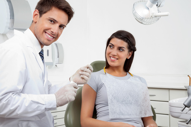 Happy Male Dentist Holding Thread While Patient Looking At Him - Foto, Imagen
