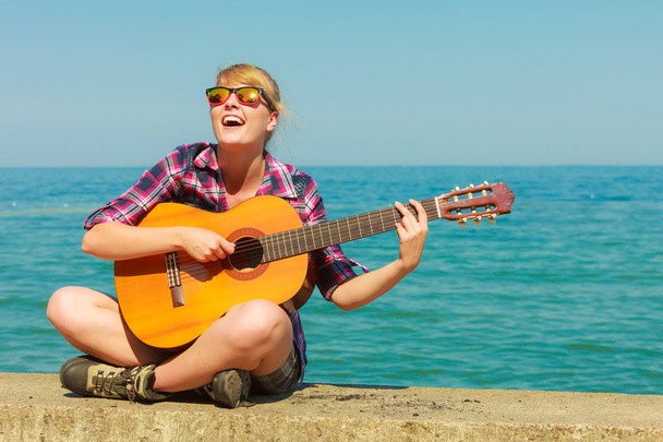 Jonge vrouw met gitaar buiten - Foto, afbeelding