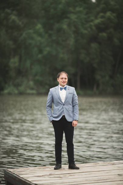 Man, groom posing near forest and lake - Фото, изображение