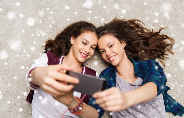 happy teenage girls on floor and taking selfie - Foto, afbeelding