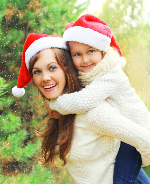 Christmas family child hugging mother in santa red hats together - Photo, Image