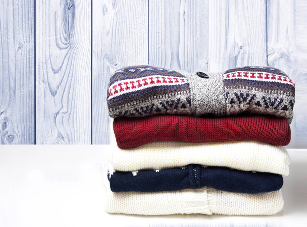 A stack of sweaters on the wooden background. - Photo, Image