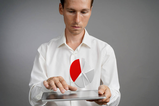 Man in white shirt working with pie chart on a tablet computer, application for budget planning or financial statistics. - Фото, зображення
