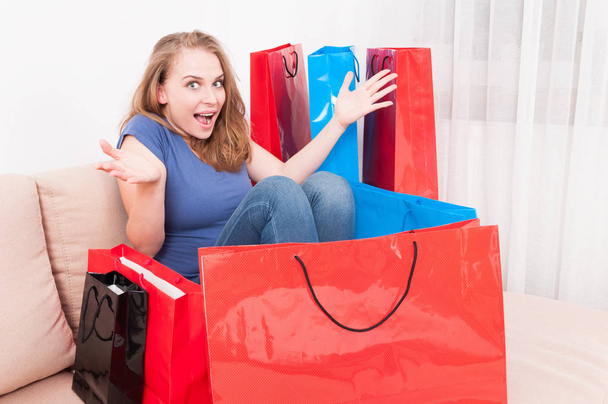 Nainen istuu sohvalla ostoskassi ympärillä käyttäytyvät iloisesti
 - Valokuva, kuva