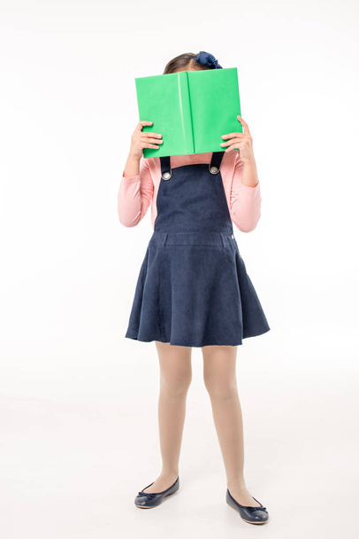 Schoolgirl hiding face with book - Фото, изображение