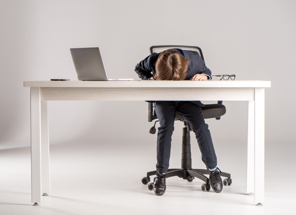 Schulkind schläft im Businessanzug auf Schreibtisch  - Foto, Bild