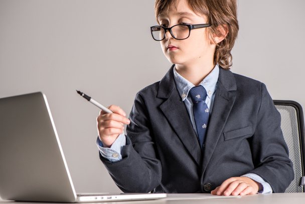 Schoolchild in business suit with pen in hands - Foto, afbeelding