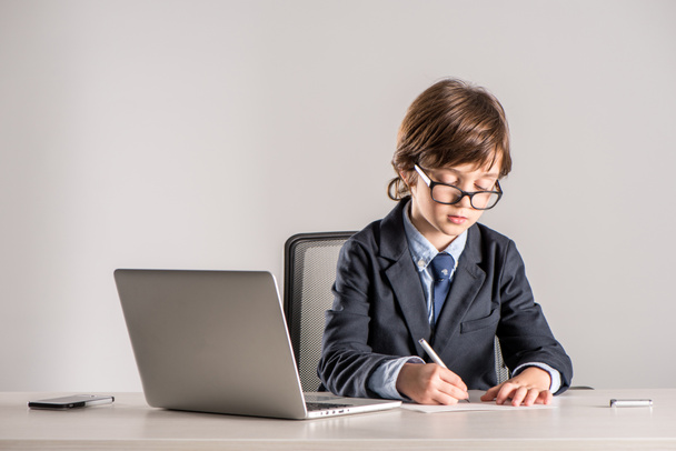 Écolière en costume d'affaires écrivant des documents
 - Photo, image