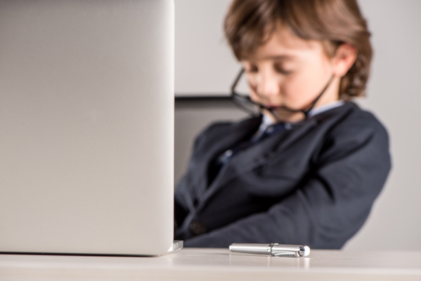 schoolchild in business suit sleeping near laptop - Фото, изображение