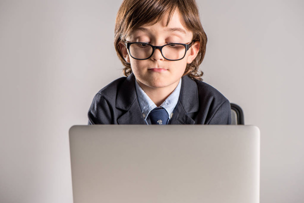 Schoolchild in business suit using laptop - Photo, Image
