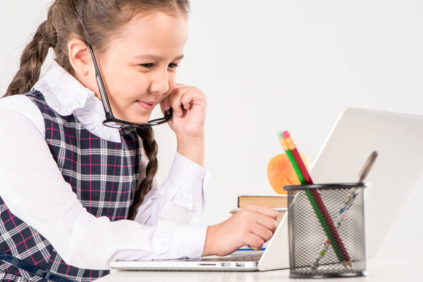 Schoolgirl at desk with laptop - Zdjęcie, obraz